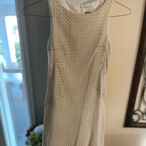 A sleeveless sheath dress. Cream herringbone lace over a gold shift.